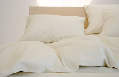 ivory colored pillowcases and duvet on a maple bed frame