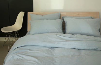 light blue colored crisp cotton duvet and pillowcases on a bed with a maple bed frame